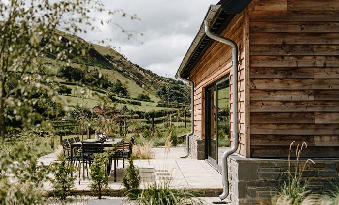 Wooded home with chairs and table outside and views of mountains beyond